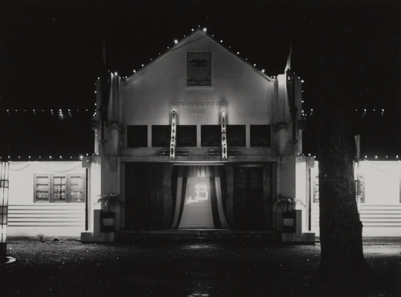 Gedung Minahasaraad malam hari diterangi cahaya pada malam perayaan pernikahan Pangeran Bernard dan putri Juliana (KITLV, 7 Januari 1937)